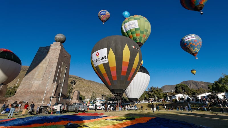 Personas observan globos aerostáticos durante la V edición del Festival de Globos, en la ciudad Mitad del Mundo, en el noroeste de Quito (Ecuador).