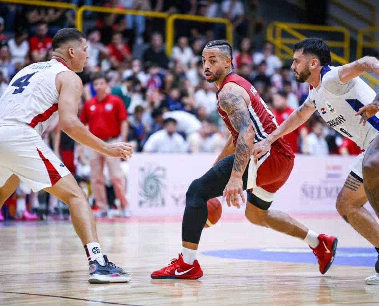 Trevor Gaskins, de Panamá, abriéndose paso entre Edgar Riveros y Juniors Peralta de Paraguay.