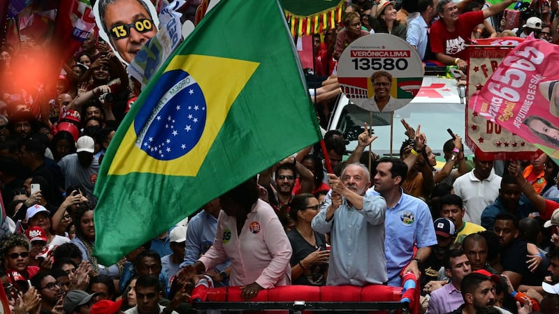 El actual presidente y candidato a la reelección, Luiz Inacio Lula da Silva (centro) ondea una bandera de su país.