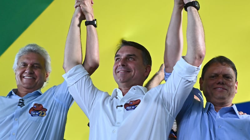 El candidato a la presidencia de Brasil, Flávio Bolsonaro (c), reacciona durante el anuncio de respaldo del exgobernador conservador Goiás Ronaldo Caiado (i), junto al gobernador reelegido de São Paulo, Tarcísio de Freitas (d), en Goiânia (Brasil). El exgobernador llamó a "derrotar al PT (Partido de los Trabajadores)" de Lula en la segunda vuelta de las presidenciales, entre los gritos de "ministro, ministro, ministro" de sus seguidores para que forme parte de un eventual gabinete del senador ultraderechista.