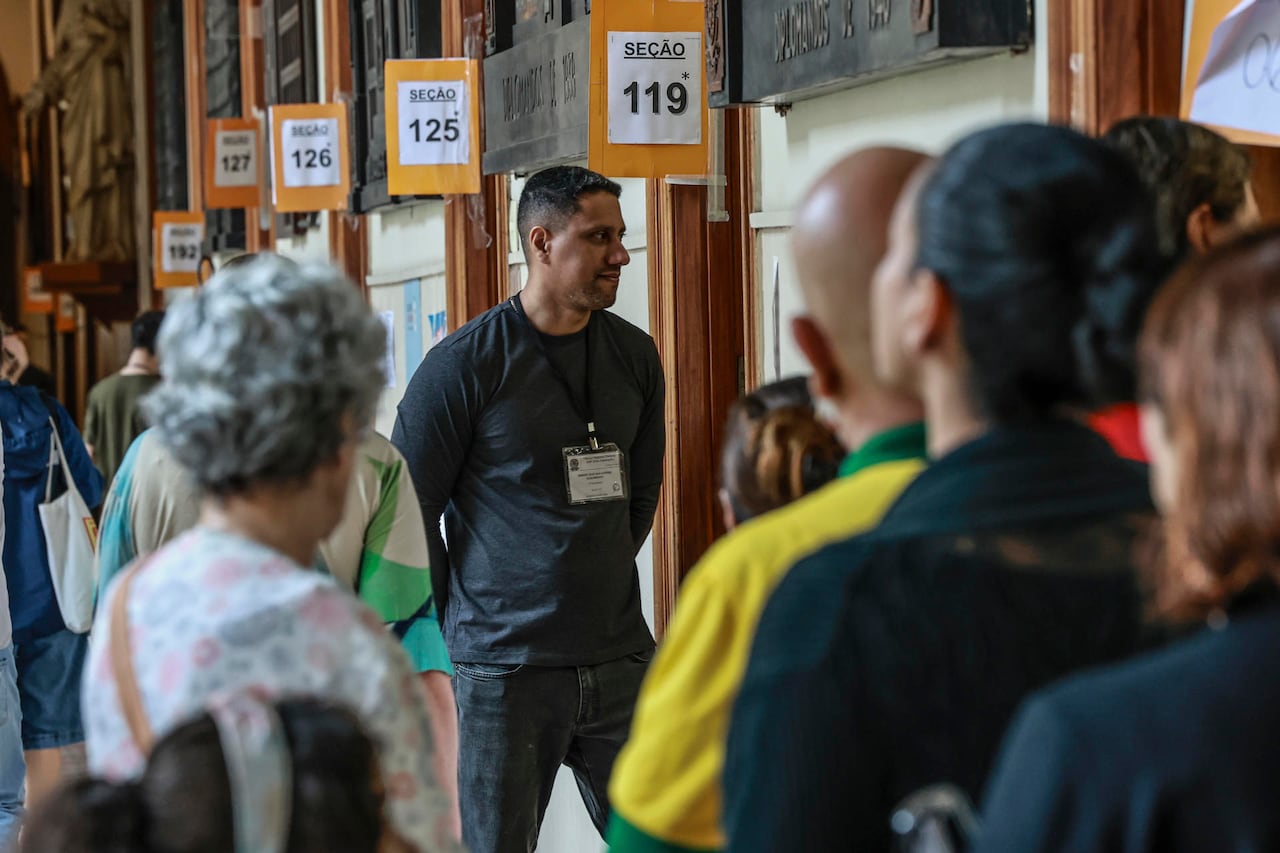 Personas esperan para votar este domingo, durante las elecciones presidenciales, legislativas y regionales, en las que el actual mandatario, Luiz Inácio Lula da Silva, busca la reelección frente a su principal rival, el senador Flávio Bolsonaro, en el barrio de Botafogo en Río de Janeiro (Brasil).