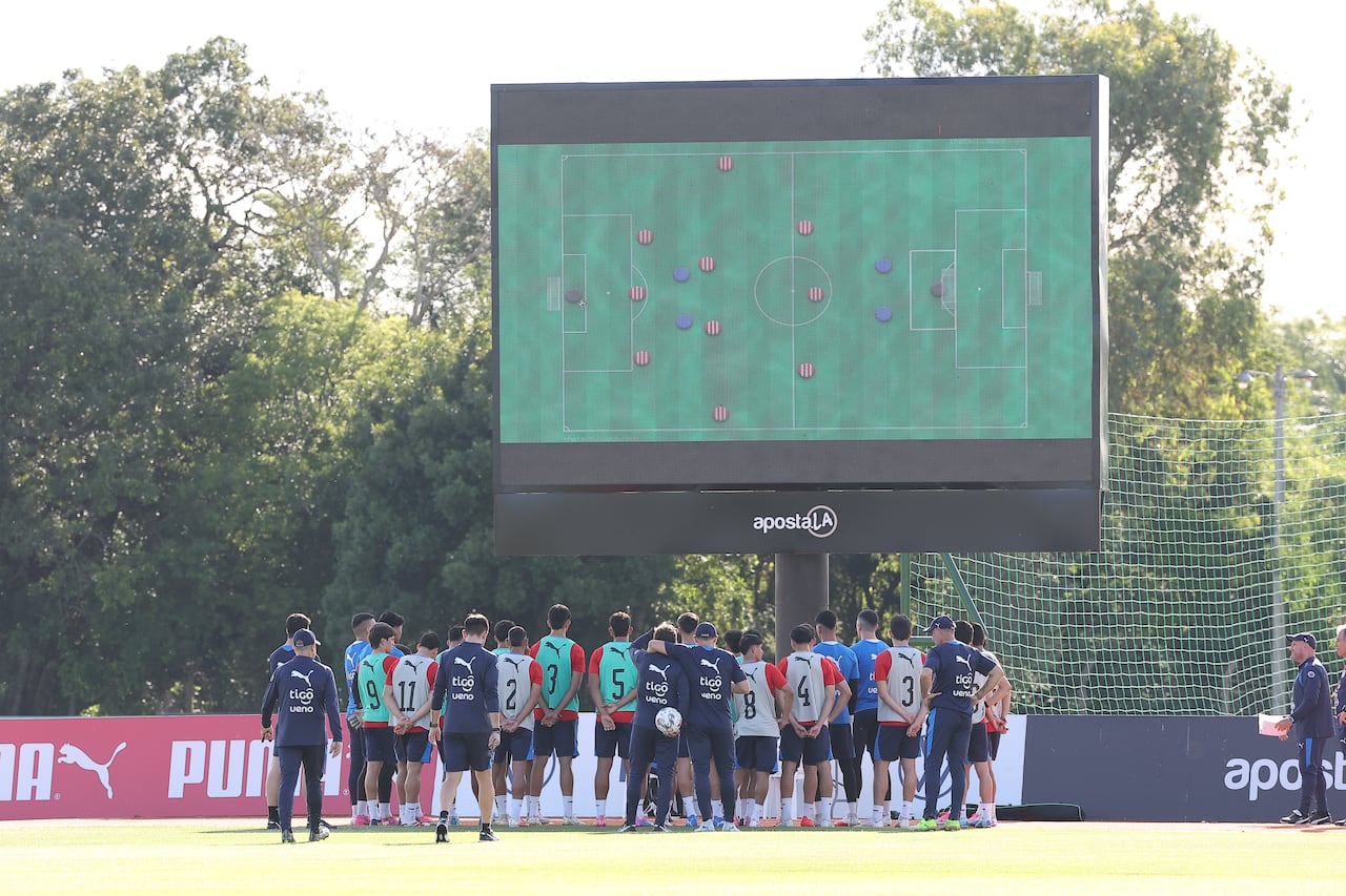 Charla previa antes del entrenamiento, pero, principalmente, nótese la pizarra con el esquema que pretende Alfaro.