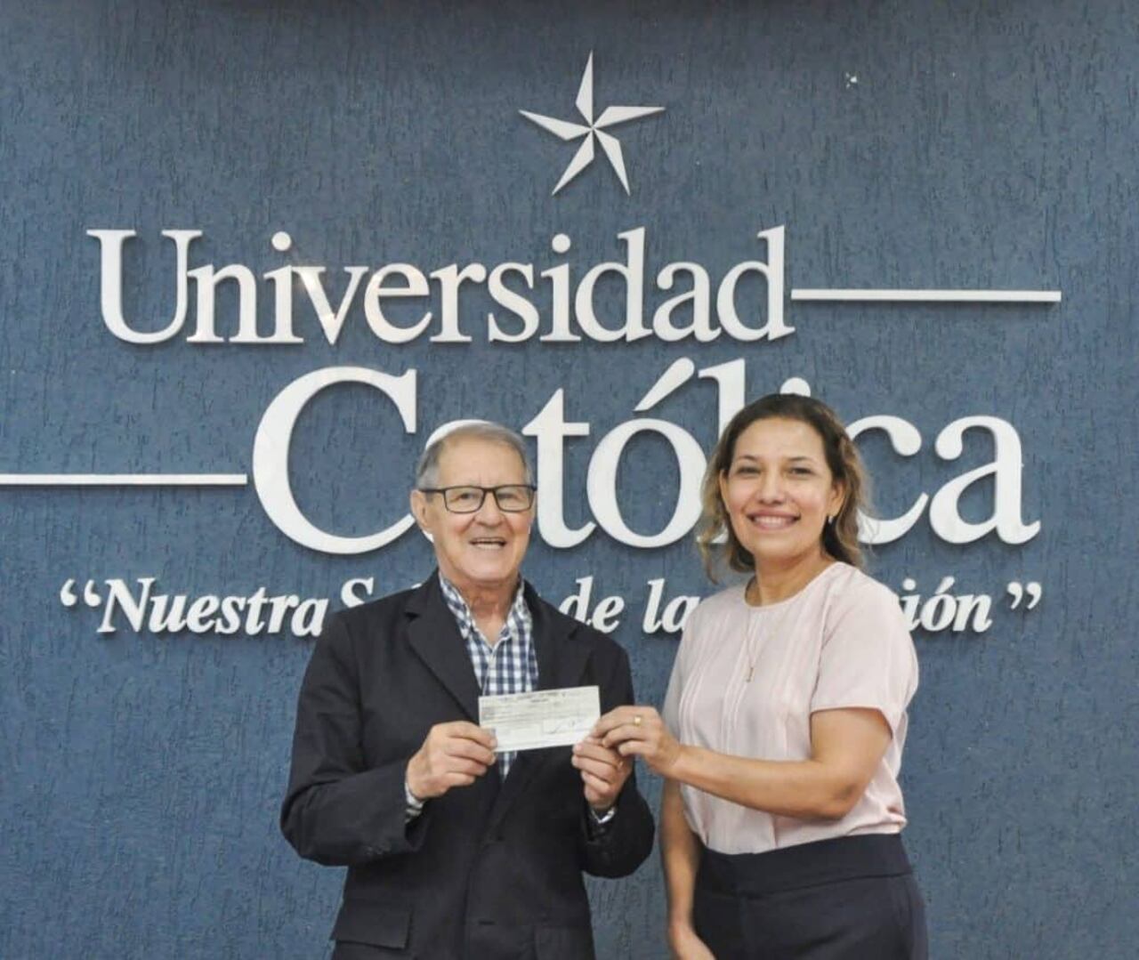 Dra. María Elena Villalba, directora general de la Universidad Católica Campus Itapúa (UCI) entrega un aporte económico a Rubén Sosa, para el sostenimiento del programa “La hora del zorzal”.