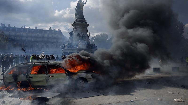 Un automóvil arde en la plaza de la República mientras estallan enfrentamientos entre manifestantes y la policía durante una protesta contra el aumento del coste de la vida y los recortes en los servicios públicos en París, Francia.