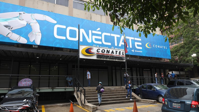 Personas caminan frente a la sede principal de la Comisión Nacional de Telecomunicaciones (CONATEL), ayer en Caracas (Venezuela). La delegación opositora que dialoga con el chavismo saludó el levantamiento de las restricciones a varios sitios web de medios de comunicación que permanecieron bloqueados por años en Venezuela e instó a que la medida aplique para todos.