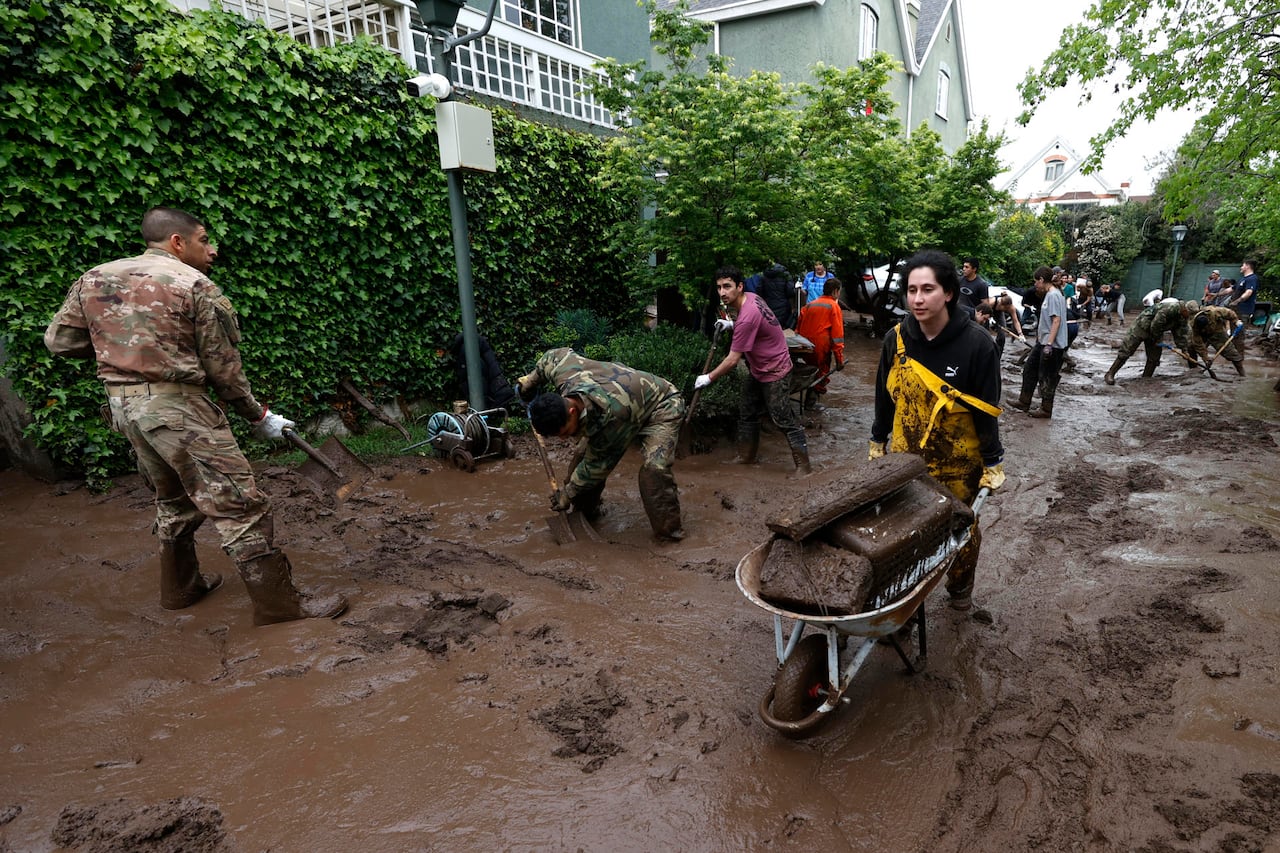 Personas trabajan en la remoción de lodo tras el paso de un aluvión en la comuna de Las Condes, en Santiago (Chile). Un aluvión por intensas lluvias que afectó a la comuna Las Condes, en el este de Santiago, y generó el arrastre de vehículos y buses en las calles, dejó 6 personas lesionadas y 600 hogares evacuados, informó el ministro del Interior de Chile, Claudio Alvarado.