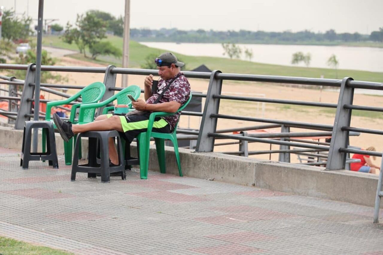 Un hombre se refresca con un tereré para sobrellevar el intenso calor de la Costanera, enAsunción.