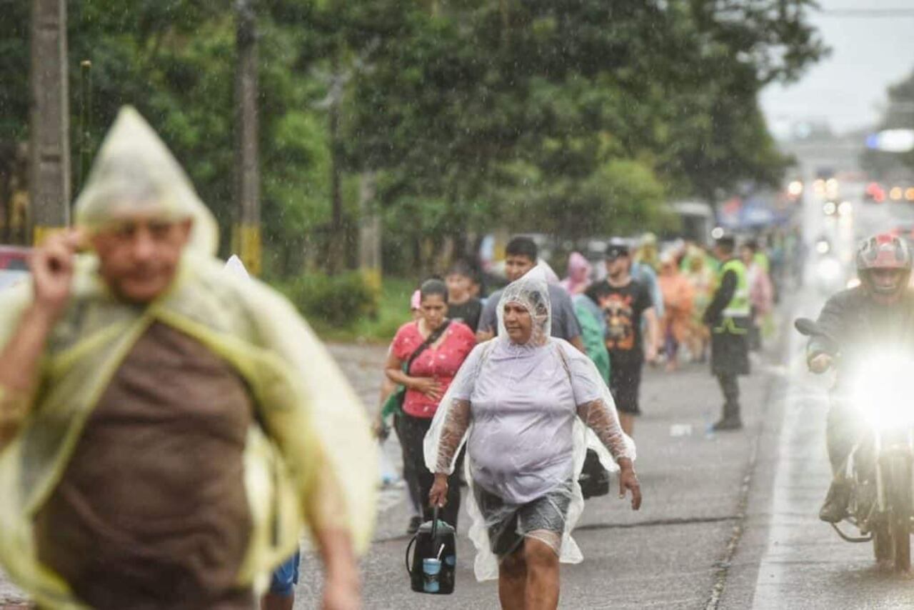 Peregrinos caminando bajo la intensa lluvia rumbo a Caacupé