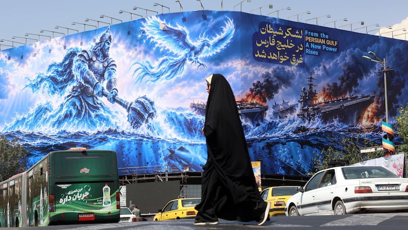 Una mujer musulmana camina frente a un mural de propaganda en Teheran, República Islámica de Irán.