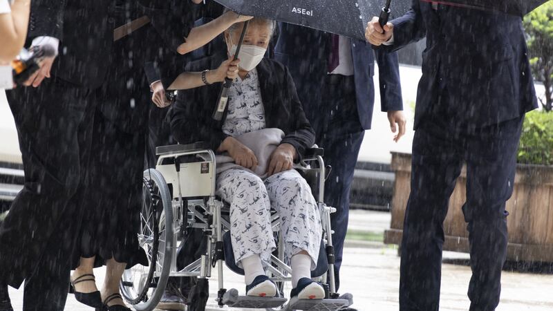 La líder de la secta Moon Han Hak-ja (centro, en silla de ruedas) sale de una Corte de Seúl.
