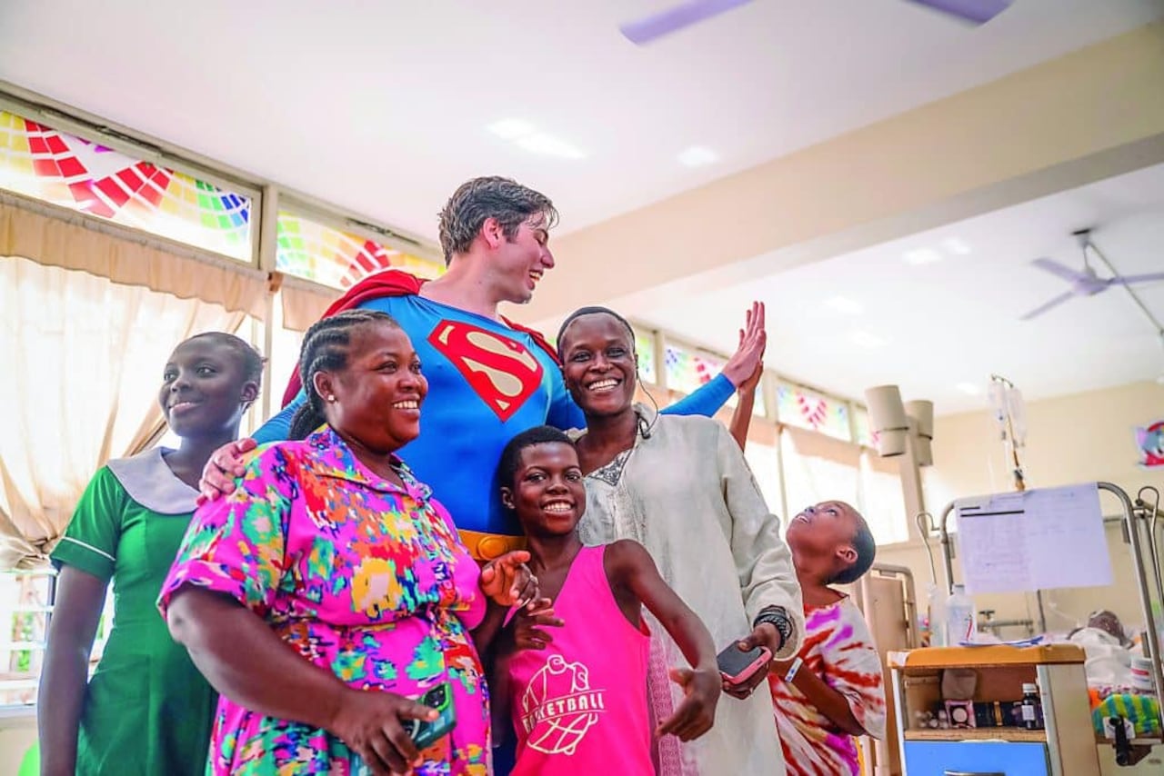 Leonardo Muylaert, known as the Brazilian Superman, poses with patients and their relatives during a visit at the Korle Bu Teaching Hospital in Accra, on November 14, 2025.